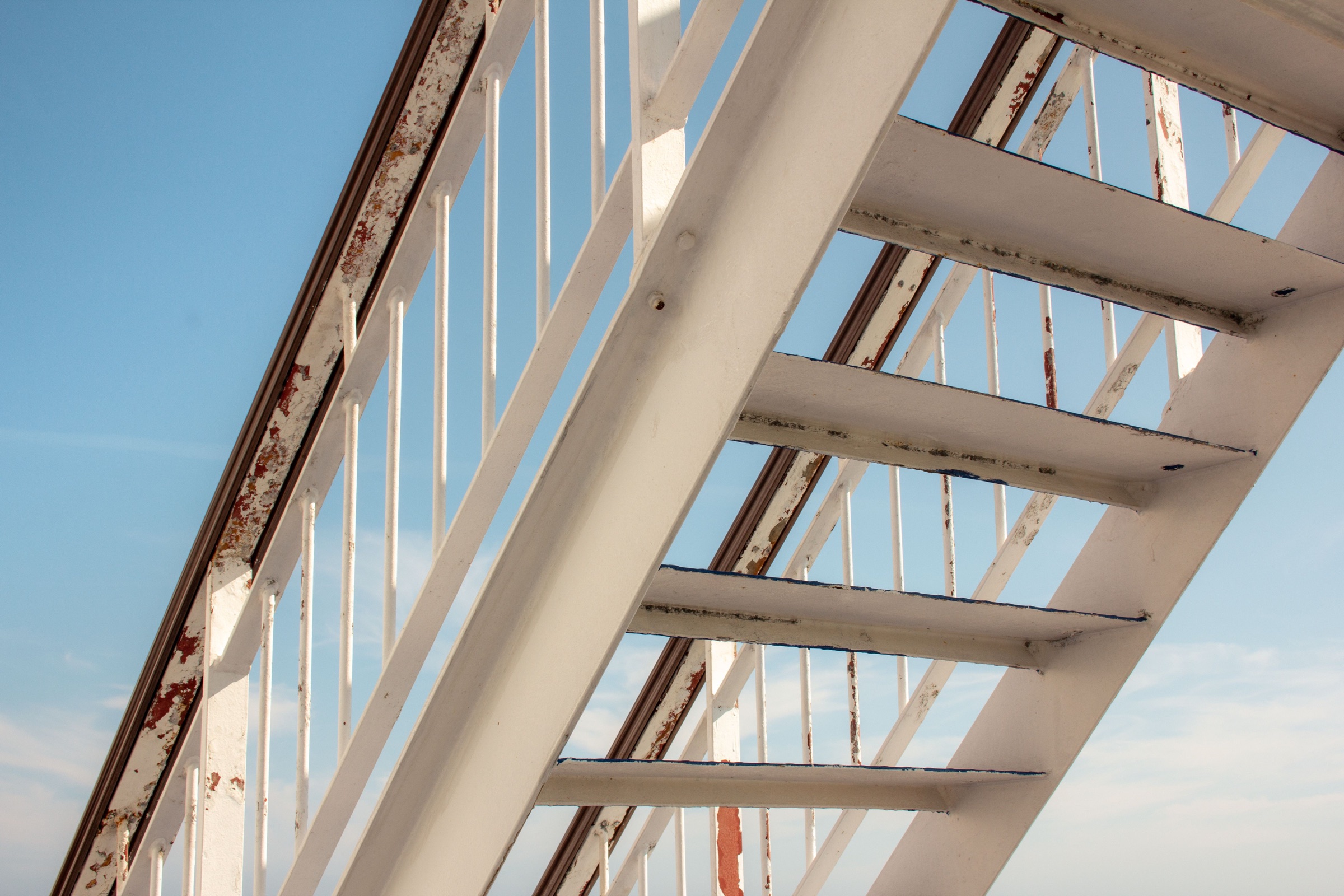 A weathered metal staircase rises against an open sky.