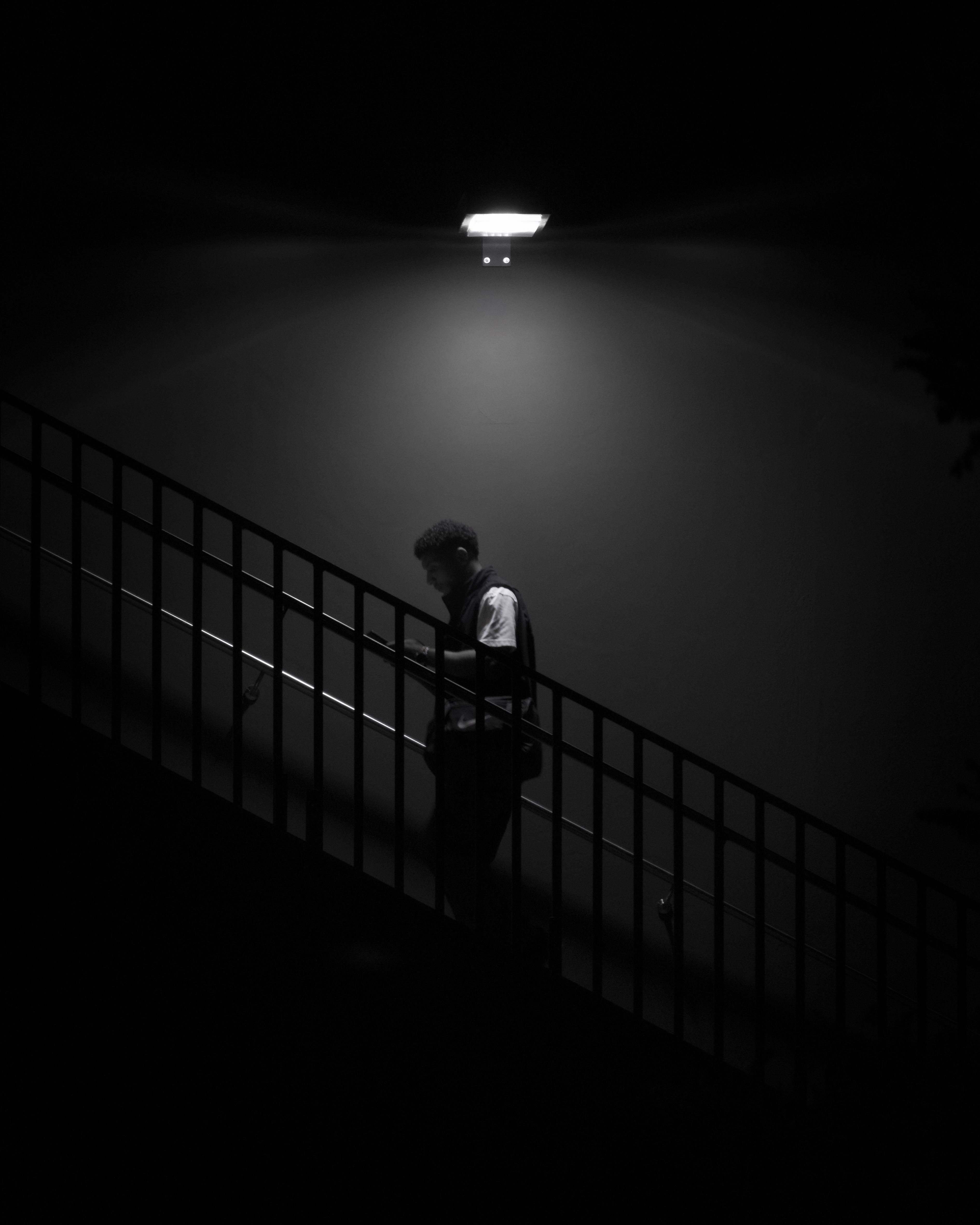 A person descends a shadowed stairwell toward the light below.